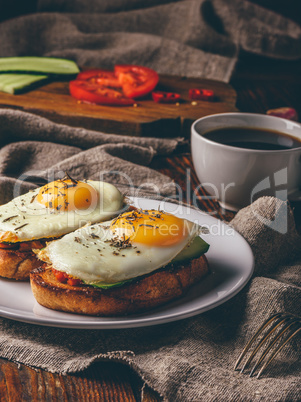 Italian toasts with vegetables and fried eggs with cup of coffee