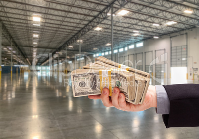 Male Hand Holding Thousands of Dollars Inside Empty Industrial W