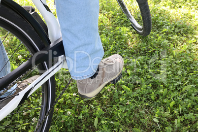 The foot in sneakers is on the pedals of the bicycle