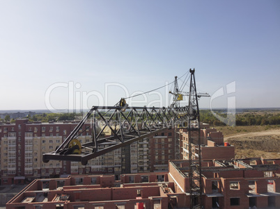 Crane over new buildings. Aerial view, cargo crane boom high in the sky