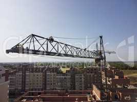 Crane over new buildings. Aerial view, cargo crane boom high in the sky