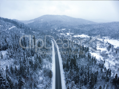 Snowy road through a wooded mountain landscape in winter. Christmas tree forest and mountain top