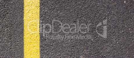 Asphalt texture with a yellow line on the left side. Road surface with markings.