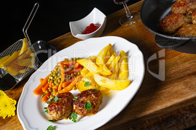 Homemade meatballs with french fries and vegetables