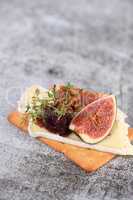 Cracker with a slice of camembert with confiture and figs