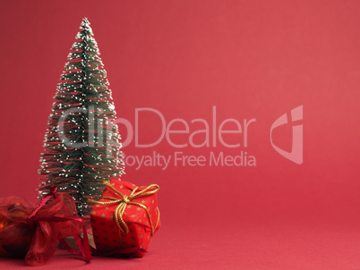 Red Christmas gift box with golden bow and decoration on a red p