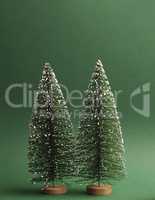 Two fir trees with snow on a green paper background, space for t