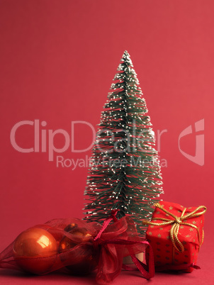 Red Christmas gift box with golden bow and decoration on a red p