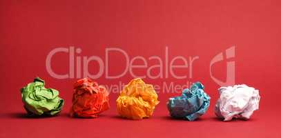 Colorful crumpled paper balls on a red studio background