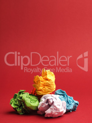 Colorful crumpled paper balls on a red studio background