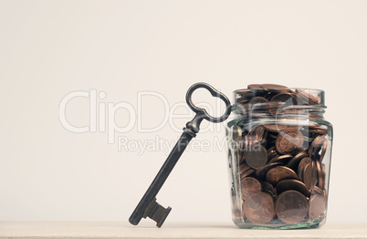 Cent and Euro coins in a canning jar, next to it is a large key,