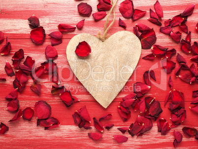 Rustic wooden heart with rose petals on wood