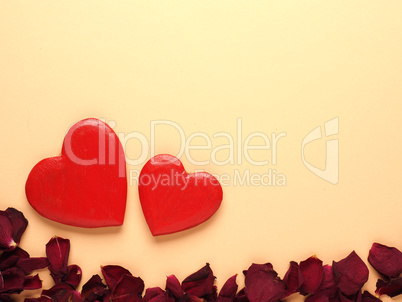 Rustic wooden hearts with rose petals on yellow background
