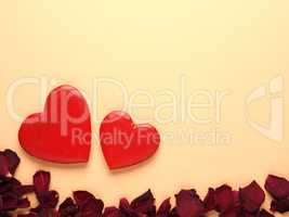 Rustic wooden hearts with rose petals on yellow background