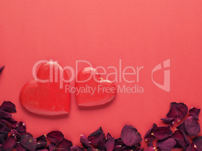 Rustic wooden hearts with rose petals on red background