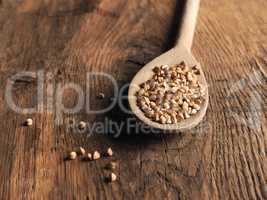 Organic buckwheat on a wooden spoon on a wooden kitchen table