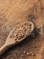 Buckwheat on a wooden spoon on a wooden kitchen table
