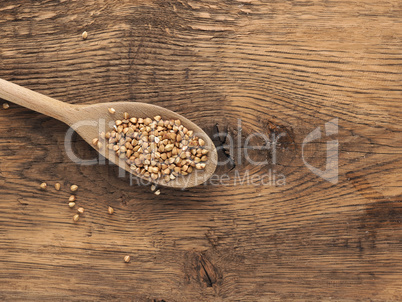 Buckwheat on a wooden spoon on a wooden kitchen table