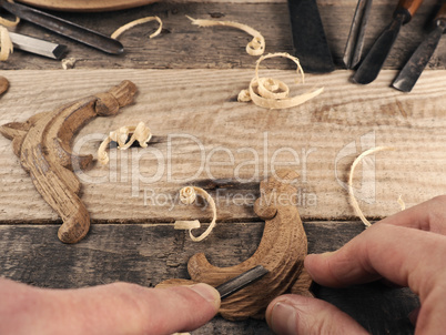 Carved oak decorative elements on a rustic workbench with chisel