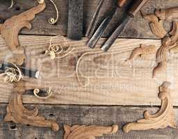 Carved oak decorative elements on a rustic workbench with chisel