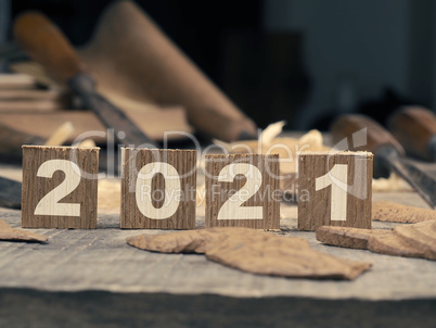 Wooden blocks with Year 2021 on a rustic workbench with chisels
