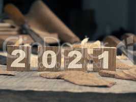 Wooden blocks with Year 2021 on a rustic workbench with chisels