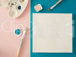 Invitation concept with a blank canvas and watercolors and brush