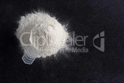 Measuring spoon with protein powder on a dark stone table, nutri
