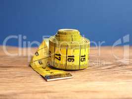 Yellow tailor tape measure on a wooden table, close up