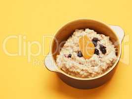 Delicious organic porridge with blueberries and apricot on a yel