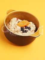 Delicious organic porridge with blueberries and apricot on a yel