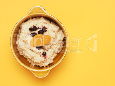 Delicious organic porridge with blueberries and apricot on a yel