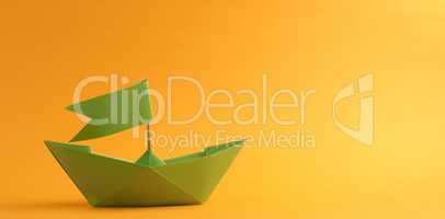 Green paper boat on a yellow background
