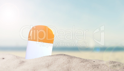 Sunscreen bottle in sand on beach with place for text