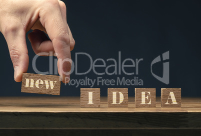 A businessman puts wooden blocks with the inscription New idea o