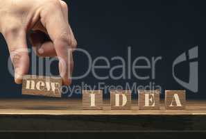 A businessman puts wooden blocks with the inscription New idea o