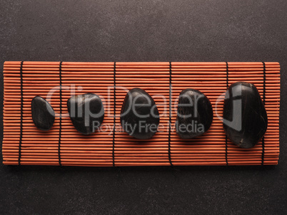 Five massage stones on a bamboo mat