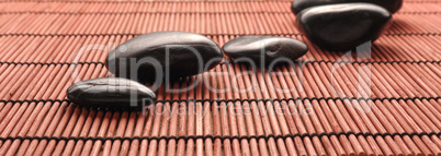 Five massage stones on a bamboo mat