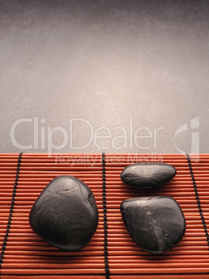Three massage stones on a bamboo mat