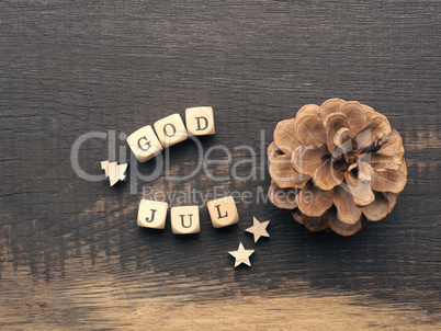 Pine cone and wooden dices with the words God Jul, Scandinavian