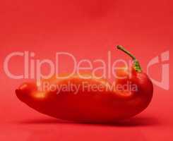 Curved red pointed peppers on a red background