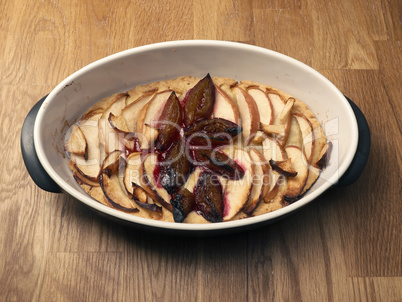 Cake with plum and apples in a baking dish