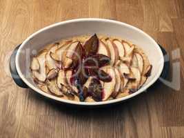 Cake with plum and apples in a baking dish