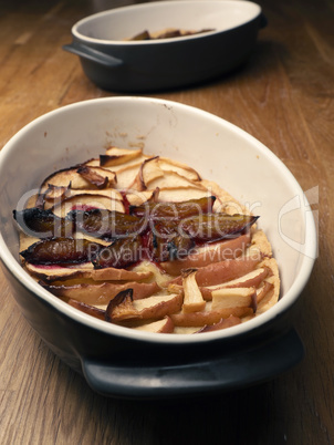 Cake with plum and apples in a baking dish