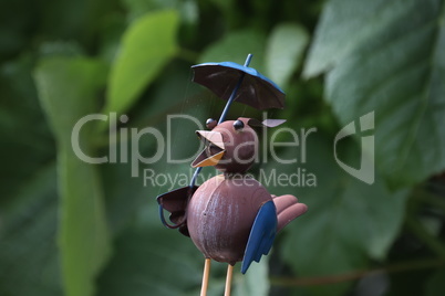 Decorative figurine of a bird stands in the garden