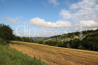 Summer landscape with harvested field and blue sky