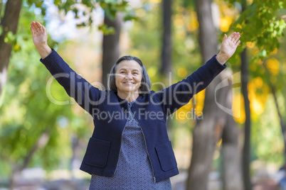 Happy woman with arms outstretched in autumn park