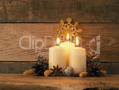 Third Advent candle burning on a rustic wooden table