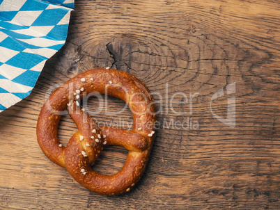 Tasty pretzel with Bavarian flag on a rustic wooden table