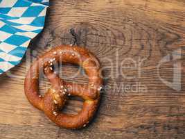 Tasty pretzel with Bavarian flag on a rustic wooden table